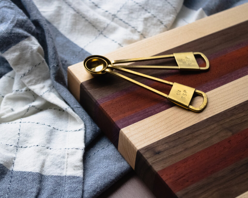 Cutting board with measuring spoons all on a tea towel
